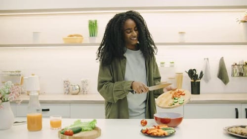 Happy Woman Dances while Preparing Salad in Kitchen