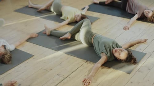 Yoga Class Exercising Lying On Mats Indoors