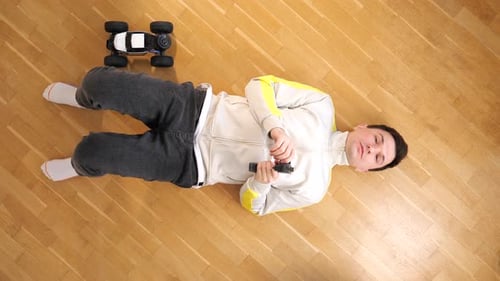 Man Lying on Floor Playing with Remote Car
