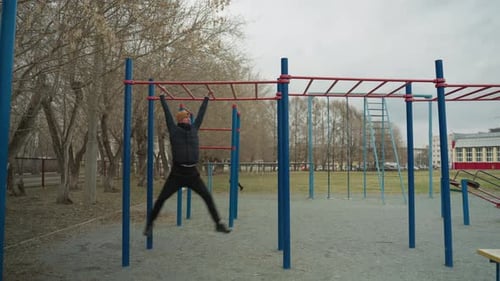 Coach Navigating Iron Bar in Urban Park with Football in Background