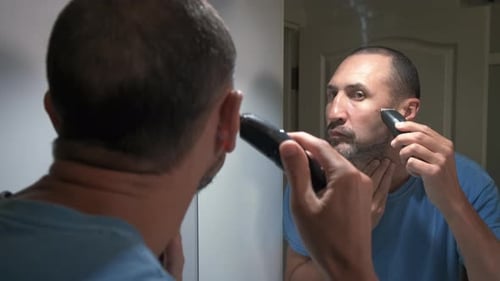 Man Trimming Beard with Electric Razor in Bathroom