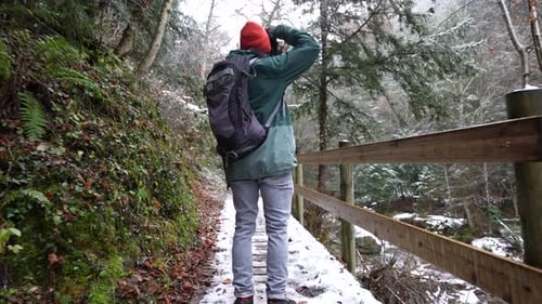 A Backpacker Photographer On Trails Taking Shots Of Scenic Views On Mountain Forest During Winter. -