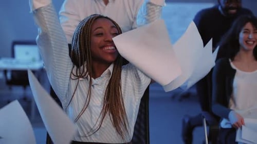 Meninos dirigindo meninas em poltronas com rodas no escritório Meninas espalhando documentos de negócios