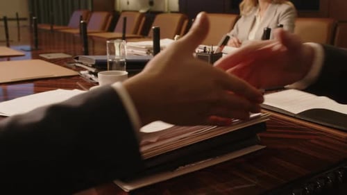 Handshake of Two Unrecognisable Lawyers at Wooden Desk in Conference Room