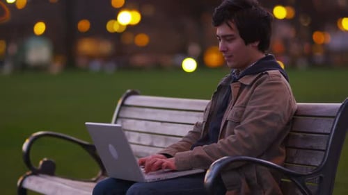 Man Sits On Park Bench Using Laptop Computer