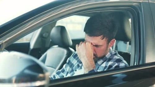 Exhausted Man Rubs Eyes in Car