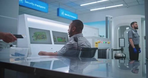 Security Officer Monitors Baggage Screening Passengers at Airport Security Checkpoint