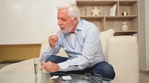 Man Taking Medication with Water in Home