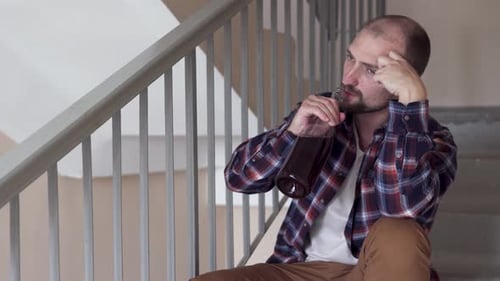Man Sits on Stairs and Drinks Wine