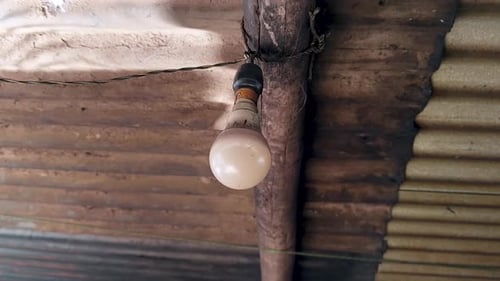 Single Hanging Light Bulb in Rustic Home Interior with Corrugated Metal Roof