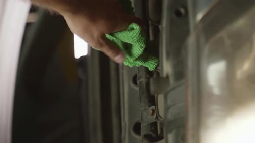 Vertikales Video: Eine Hand hält einen gelben Ölmessstab und steckt ihn in einen Automotor, um den Ölstand zu überprüfen