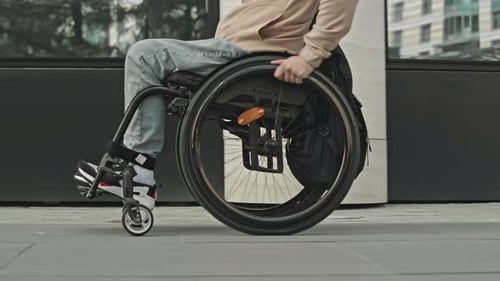 Wheelchair User Riding along City Street