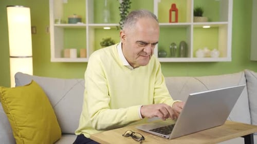 Senior Man Types on Laptop at Home