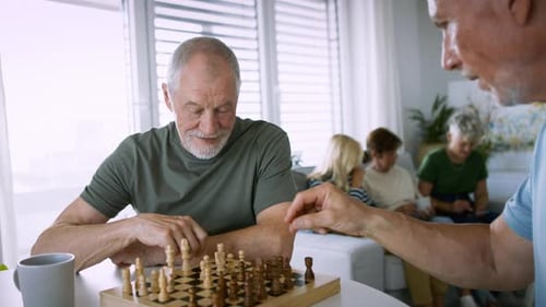 Senior Men Playing Chess with Family in Background