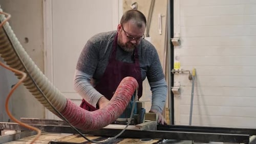 Carpenter Feeds Wood Through a Table Saw Hands Guiding with Expertise The Scene Underscores the