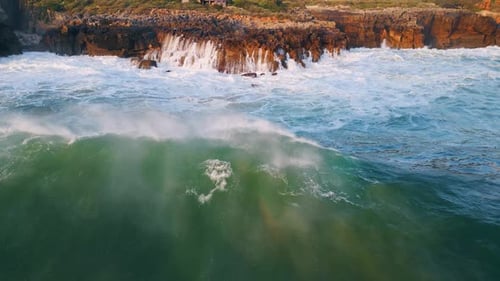 Drone view of foaming water splashing rocks at stunning coastal cliffs on summer day