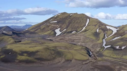 Forward drone view towards a green mountain near Bláhylur Lake in Landmannalaugar, iceland.