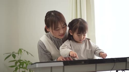 Woman and Child Play Keyboard Together Indoors