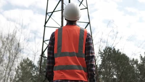 A power engineer inspects a high-voltage power line using data from electrical sensors on a tablet.