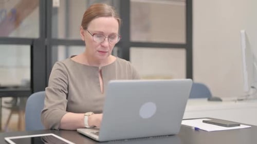 Coughing Old Businesswoman Using Laptop in Office