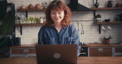 Woman Opens Laptop in Stylish Kitchen