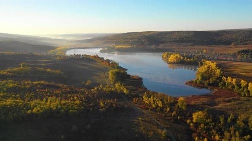 aerial view of beautiful autumn fall morning above lake with trees with yellow leaves