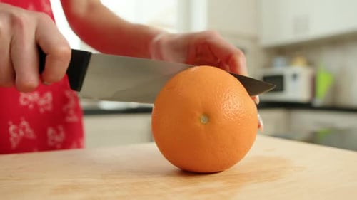 Mujer corta una naranja por la mitad