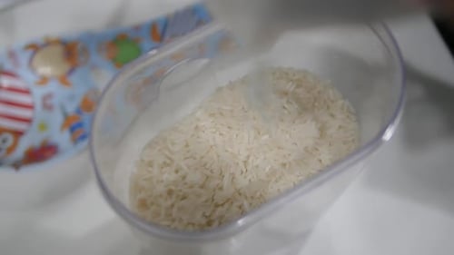 Rice Grains Pouring into Plastic Container