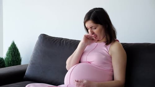 Pregnant Woman Coughing on Couch, Feeling Ill