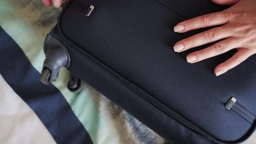 Woman Zipping Up a Dark Blue Suitcase