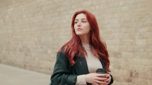 Redhead Woman Enjoys Coffee on City Stroll