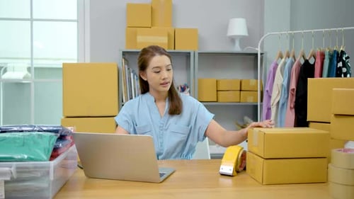 Woman Using Laptop with Boxes in Background