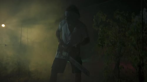 Silhouette Of A Crazy Man Fight With Chainsaw In Night Forest