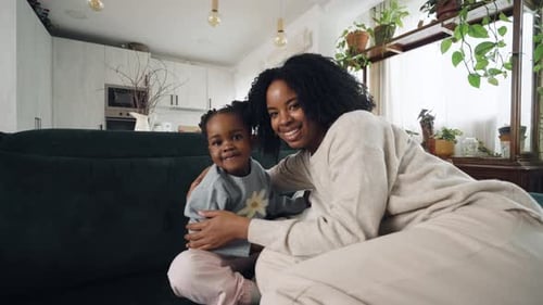 Woman Cuddling Child on Couch in Modern Home
