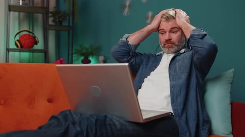 Man Working on Laptop at Home Looks Worried