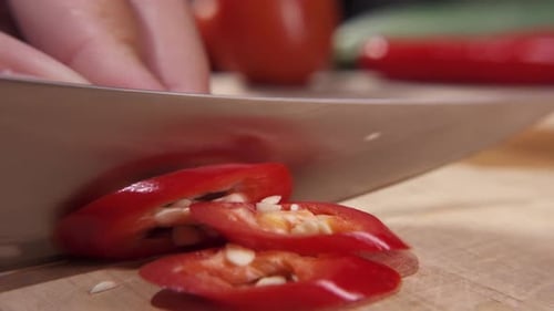Cutting fresh red chili pepper with a sharp knife