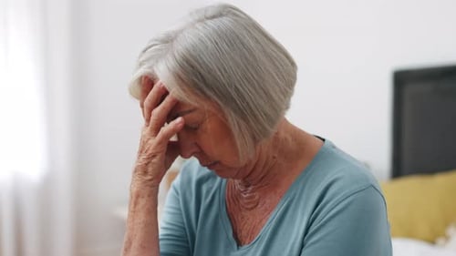 Headache, senior woman and stress in home for retirement, mental health and anxiety of depression