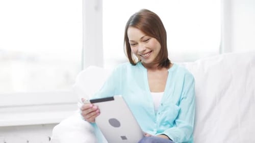 Smiling Woman Using Tablet on Sofa at Home