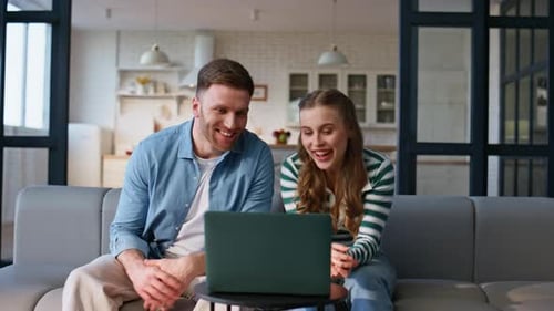 Happy Couple Video Chatting on Laptop at Home