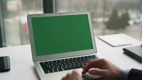 close-up of male hands flipping the touchpad of a laptop with chroma key on the screen