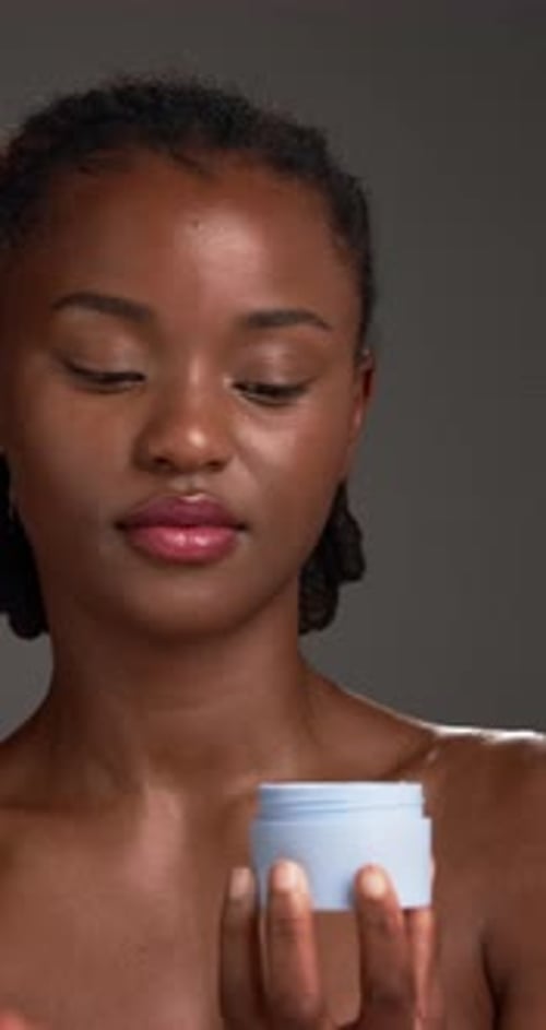 Cream, skincare and black woman with beauty, container and dermatology on grey studio background