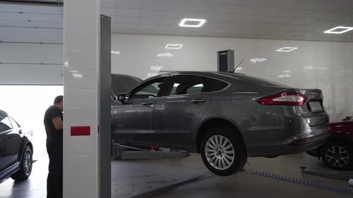 Auto Technician Inspects Vehicle on Lift Checking Oil Replacing Filter Topping Off Fluids in Clean