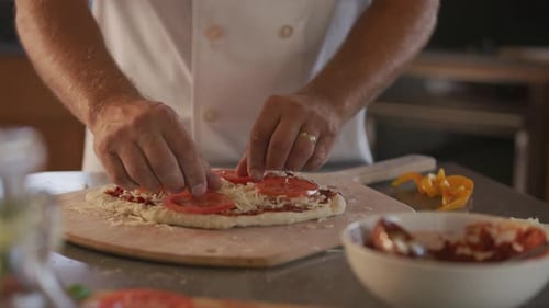 Die Hände des Küchenchefs fügen Pizzabeläge hinzu