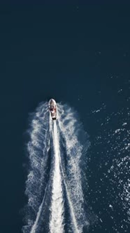 Aerial View of a Jet Ski Speeding Across Dark Blue Water Leaving a Dynamic White Trail Captured By