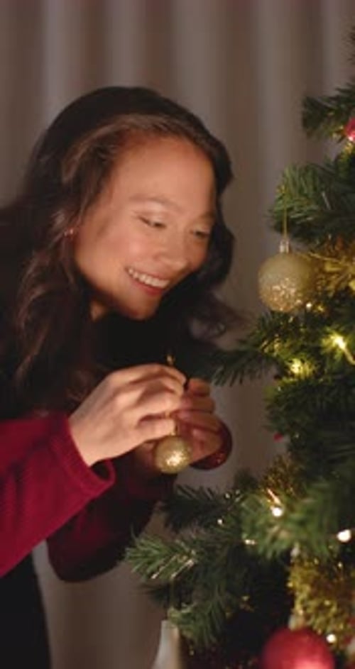 Woman Decorating Christmas Tree with Shiny Ornament