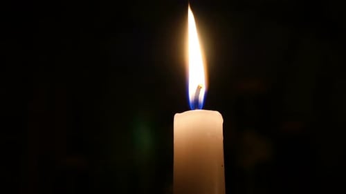 Candle burning brightly in the dark, close up view