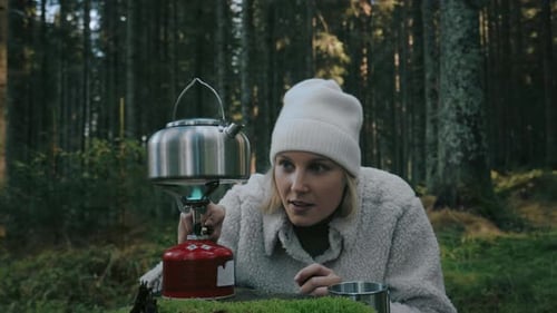 Close up shot of woman setting up a camping stove in mountain forest to make warm some water for tea