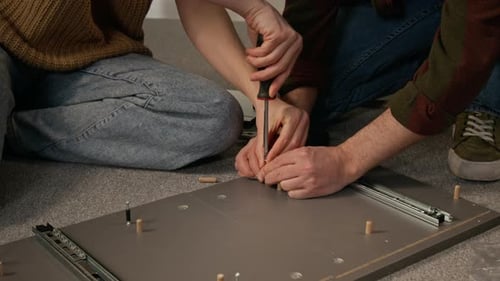 Hands of Couple Inserting Fixtures with Screwdriver while Assembling Drawer