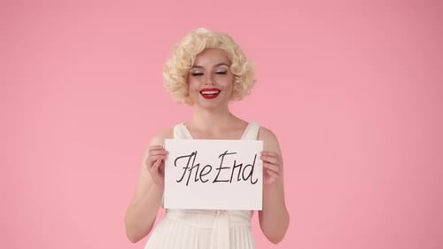 Portrait of a Woman Holding a Poster with the Inscription of the End Woman in the Look of in Studio