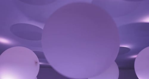 White Balloons Floating Under a Purple Lit Ceiling
